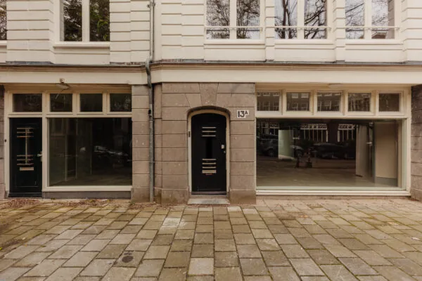 Voorgevel van een pand aan de Henri Polaklaan 13A met een zwarte deur en grote ramen op de begane grond.